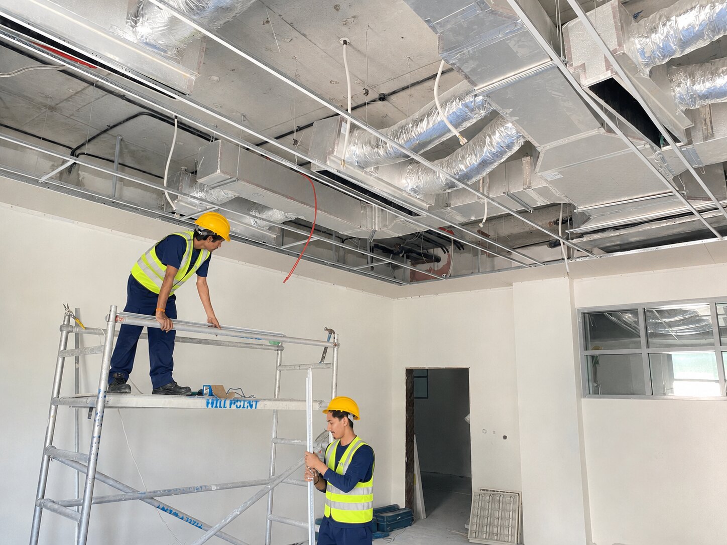 White Waves team in safety equipment installing a suspended ceiling grid